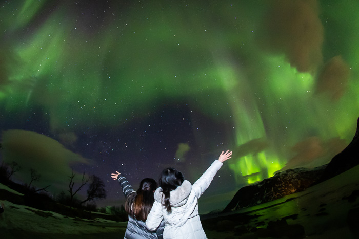 foto de chicas saludadando a la aurora boreal por fotógrafo de bodas diferente